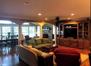 Relax in a spacious living room with a high ceiling, comfortable seating area, and stone fireplace.