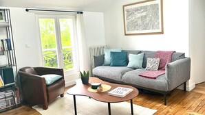A living room with a grey sofa, a brown armchair, a coffee table, and a bookshelf. - Attractive architect-designed apartmenteur 3 rooms 10 mn from Paris Montparnasse (Malakoff)
