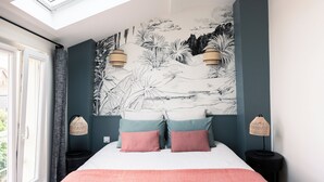 A bedroom with a skylight, a bed with pink and blue pillows, a wall mural, and two bedside lamps. - Attractive architect-designed apartmenteur 3 rooms 10 mn from Paris Montparnasse (Malakoff)
