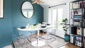 A dining area with a white table, clear chairs, and a potted plant. - Attractive architect-designed apartmenteur 3 rooms 10 mn from Paris Montparnasse (Malakoff)