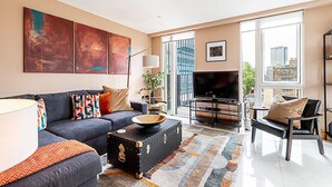 A modern living room with a sofa, a coffee table, a TV, and a large window.