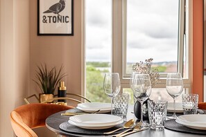 A dining table set with plates, glasses, and cutlery, a vase with flowers, and a framed sign on the wall. - Convenient Euston London Apartment (London)