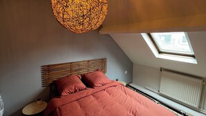 Ein Schlafzimmer mit einem großen Bett, einem Oberlicht und einer Pendelleuchte.