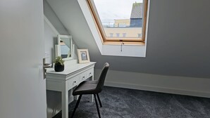 Une petite chambre à coucher moderne, avec un plafond en pente et un puits de lumière.