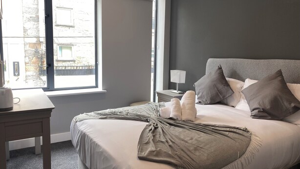 Une chambre d’hôtel avec un lit, une table de chevet, une lampe et une vue sur l’extérieur.