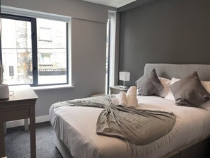 Relax in a serene space with a large bed, white linens, and a soft reading light.