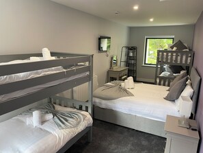 Relax in a cozy space with a bunk bed, bedside table, and desk, offering a peaceful view of the surrounding greenery.