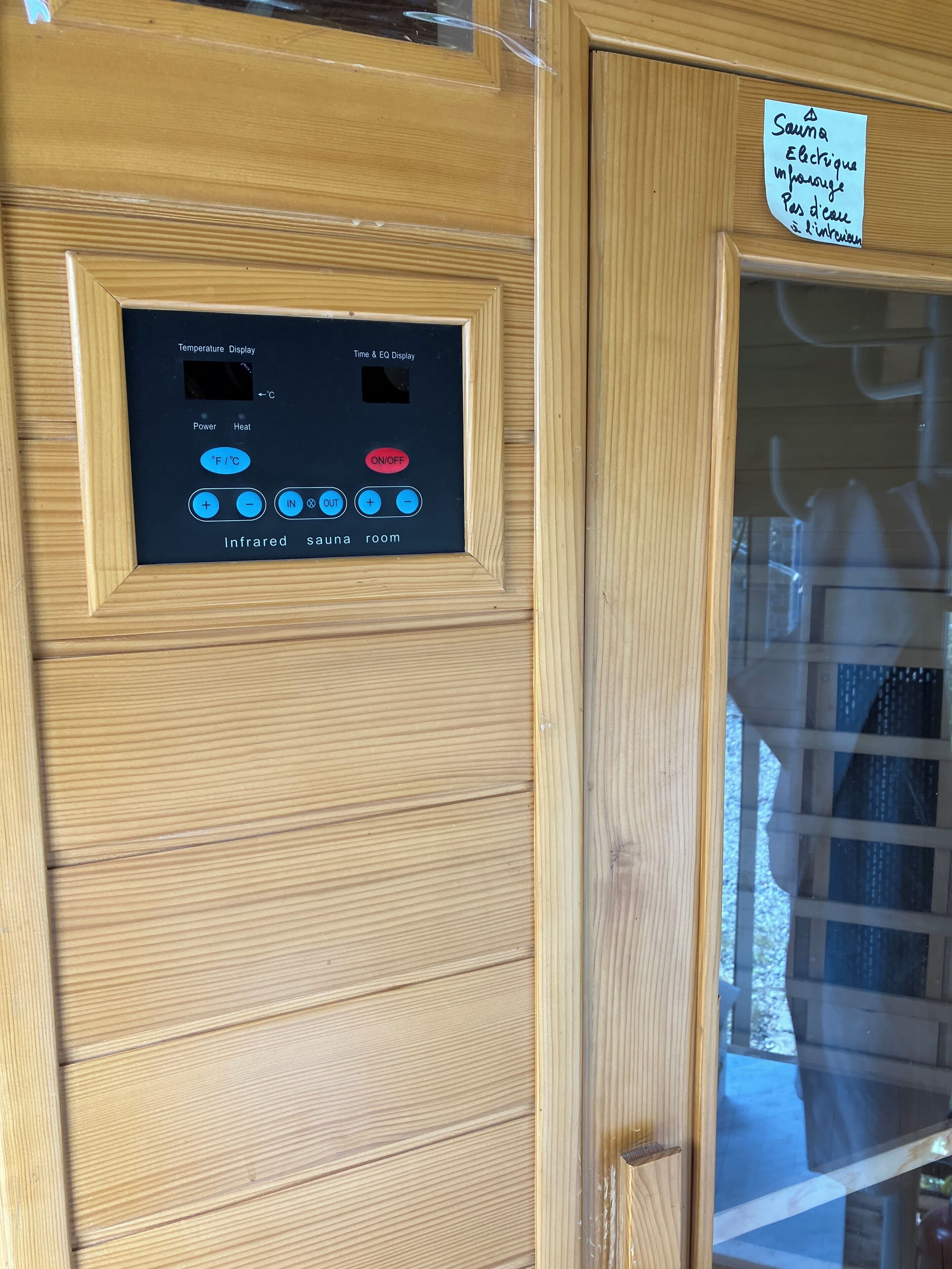 Una puerta de madera con un panel de control de sauna y una nota manuscrita.