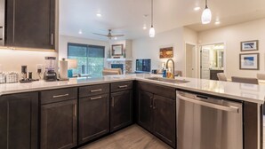 A modern kitchen with dark cabinets, a dishwasher, and a large island. - Clearwater Lofts #302, Building 3 By Summit County Mountain Retreats (Keystone)