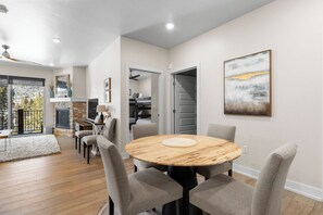 A modern dining area with a round wooden table, grey upholstered chairs, and a painting on the wall. - Clearwater Lofts #302, Building 3 By Summit County Mountain Retreats (Keystone)