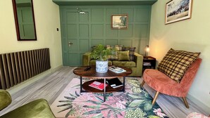A living room with a green door, a sofa, a coffee table with a plant, and a rug. - Boutique Castle View 3 Bed, 1 Bath Apartment

​ (Edinburgh)