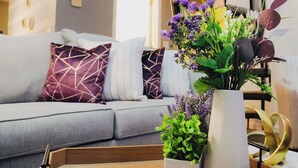 Un soggiorno moderno con un divano grigio, cuscini decorati e un vaso con fiori.