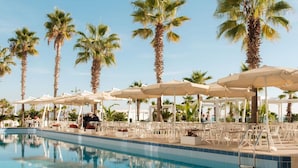 A poolside area with lounge chairs and umbrellas, surrounded by palm trees. - Palace Hotel & SPA (Durrës)