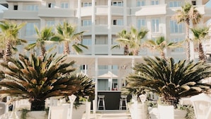 A multi-story hotel with a central courtyard, palm trees, and outdoor seating. - Palace Hotel & SPA (Durrës)