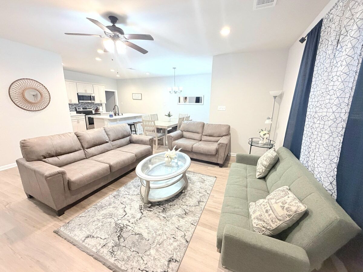 A modern living room with a sofa set, a coffee table, and a dining area with a table and chairs.