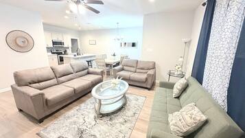 A modern living room with a sofa set, a coffee table, and a dining area with a table and chairs.