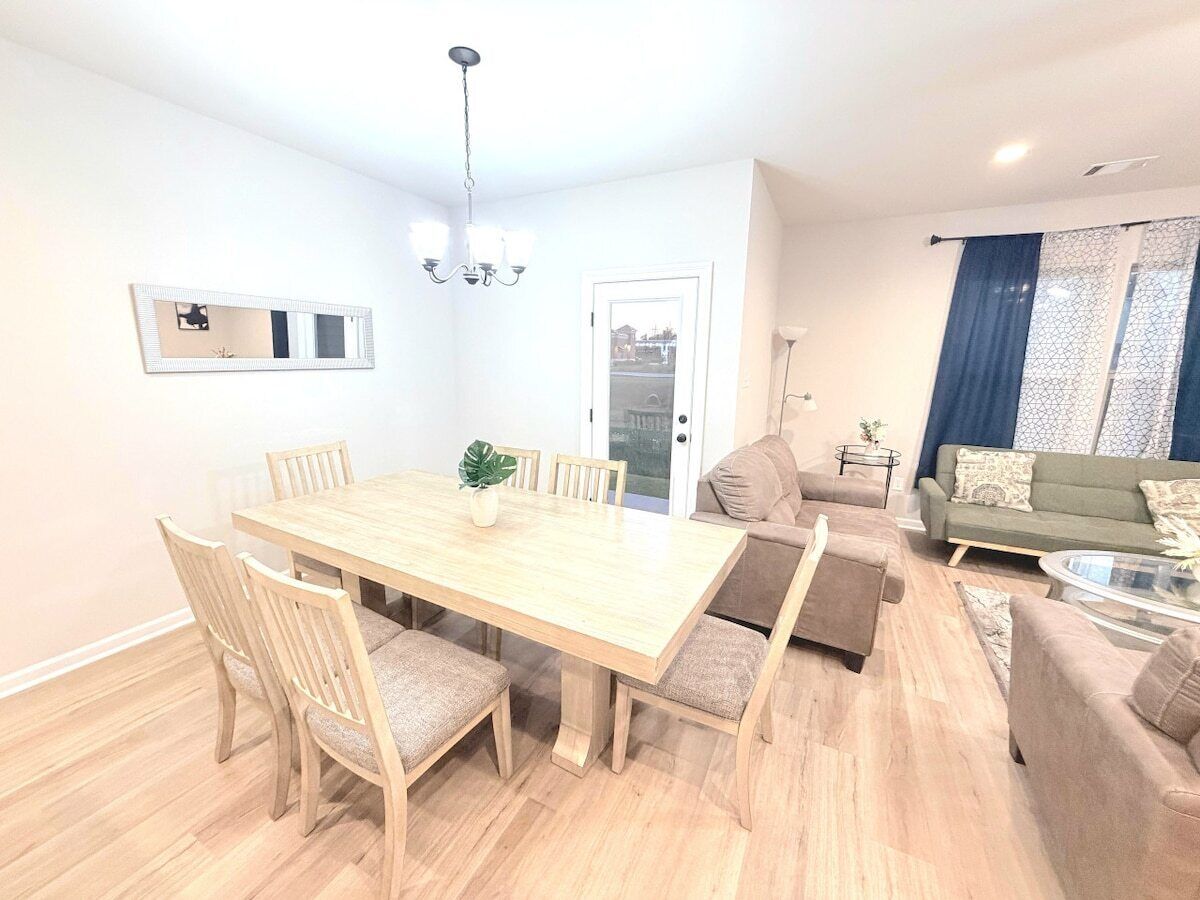 A modern living room with a wooden dining table, sofas, and a glass coffee table.