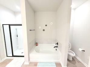 A bathroom with a bathtub, toilet, and shower area.