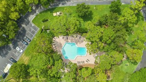 Vista aérea de una propiedad con piscina rodeada de árboles, aparcamiento y campo de golf.