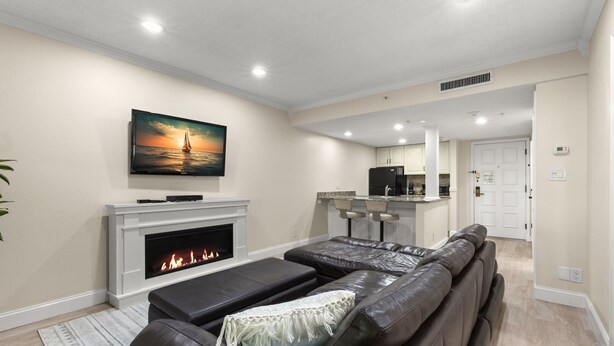 Una sala de estar moderna con chimenea, sofá de cuero y televisor montado en la pared.