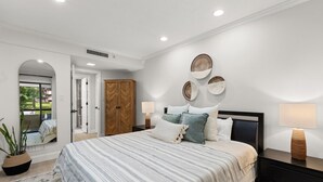 Un dormitorio con una cama grande, un armario, una mesita de noche con una lámpara y un espejo.