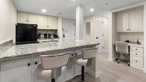 Una cocina moderna con encimera de granito, electrodomésticos de acero inoxidable y muebles de cocina blancos.