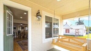 A porch with a swing, a dining area, and a house number 1102. - Experience Cheyenne in a cozy home, close to Downtown, Medical Center and CFD.  (Cheyenne)