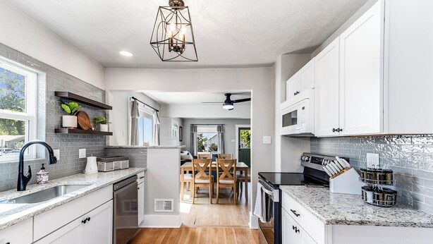 A modern kitchen with white cabinets, granite countertops, and a central island. - Experience Cheyenne in a cozy home, close to Downtown, Medical Center and CFD.  (Cheyenne)