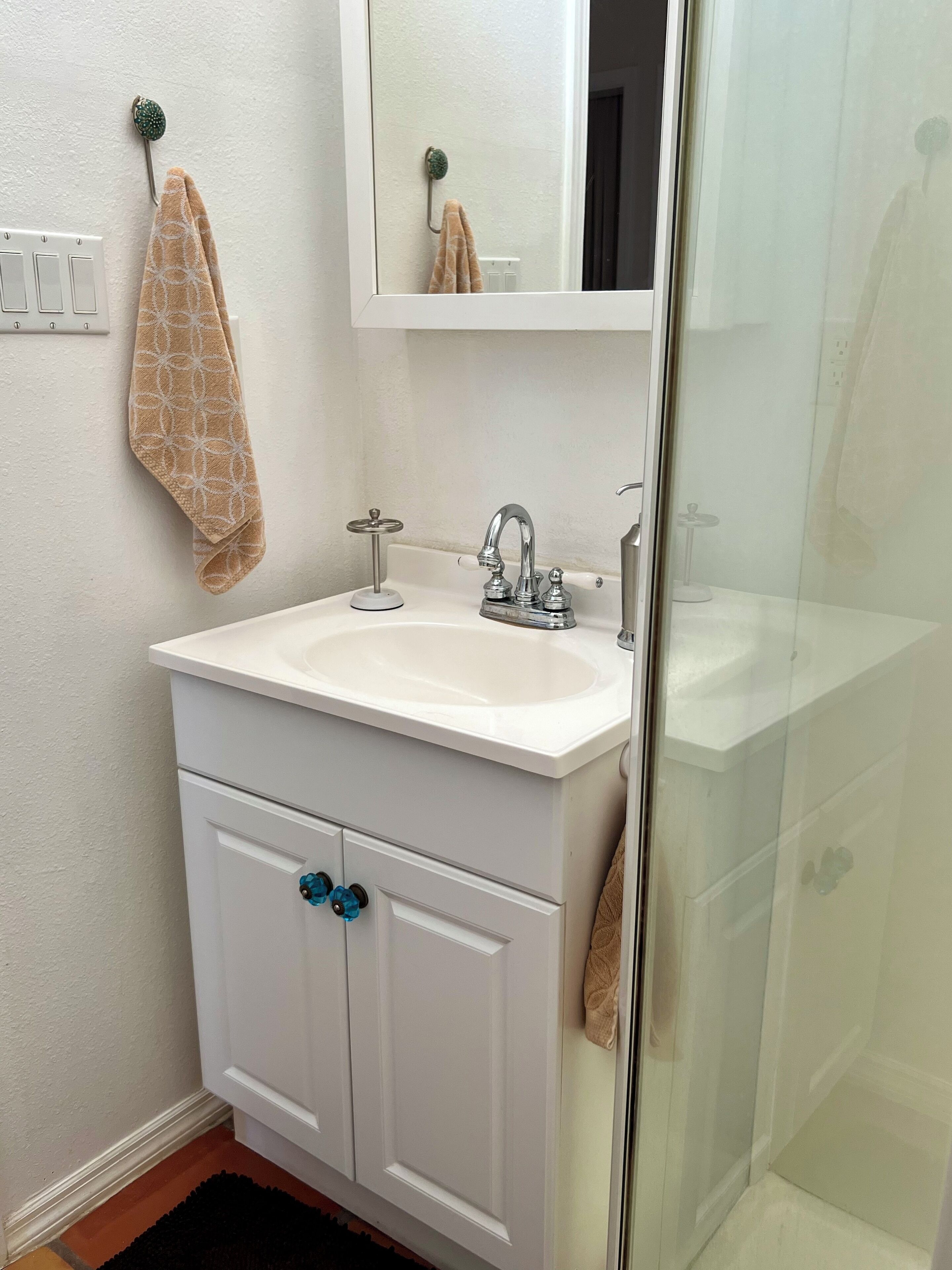 A bathroom with a white sink, a mirror, and a glass shower enclosure.