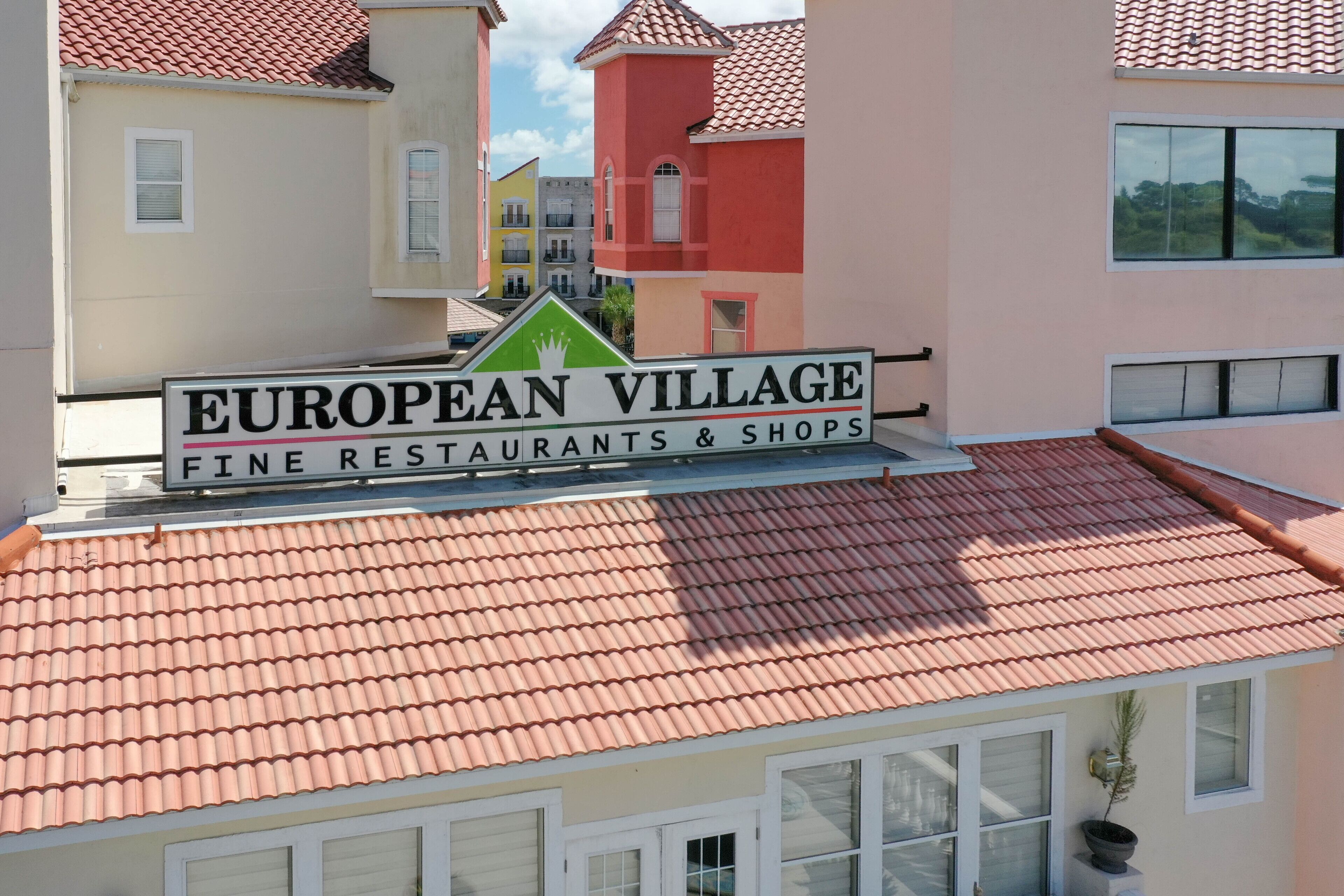 A sign for "European Village Fine Restaurants & Shops" on a building with a red-tiled roof.