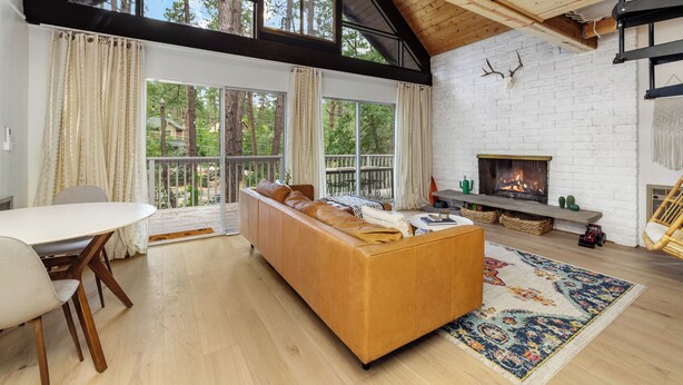 A spacious living room with a large sofa, a dining table, and a fireplace. - Silver King Cabin. 6,200 ft of elevation. 10 minutes from downtown Prescott.  (Prescott)