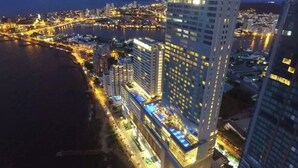 Et højt hotel med et tydeligt skilt, "Hyatt Regency", omgivet af bylys og et vandareal.