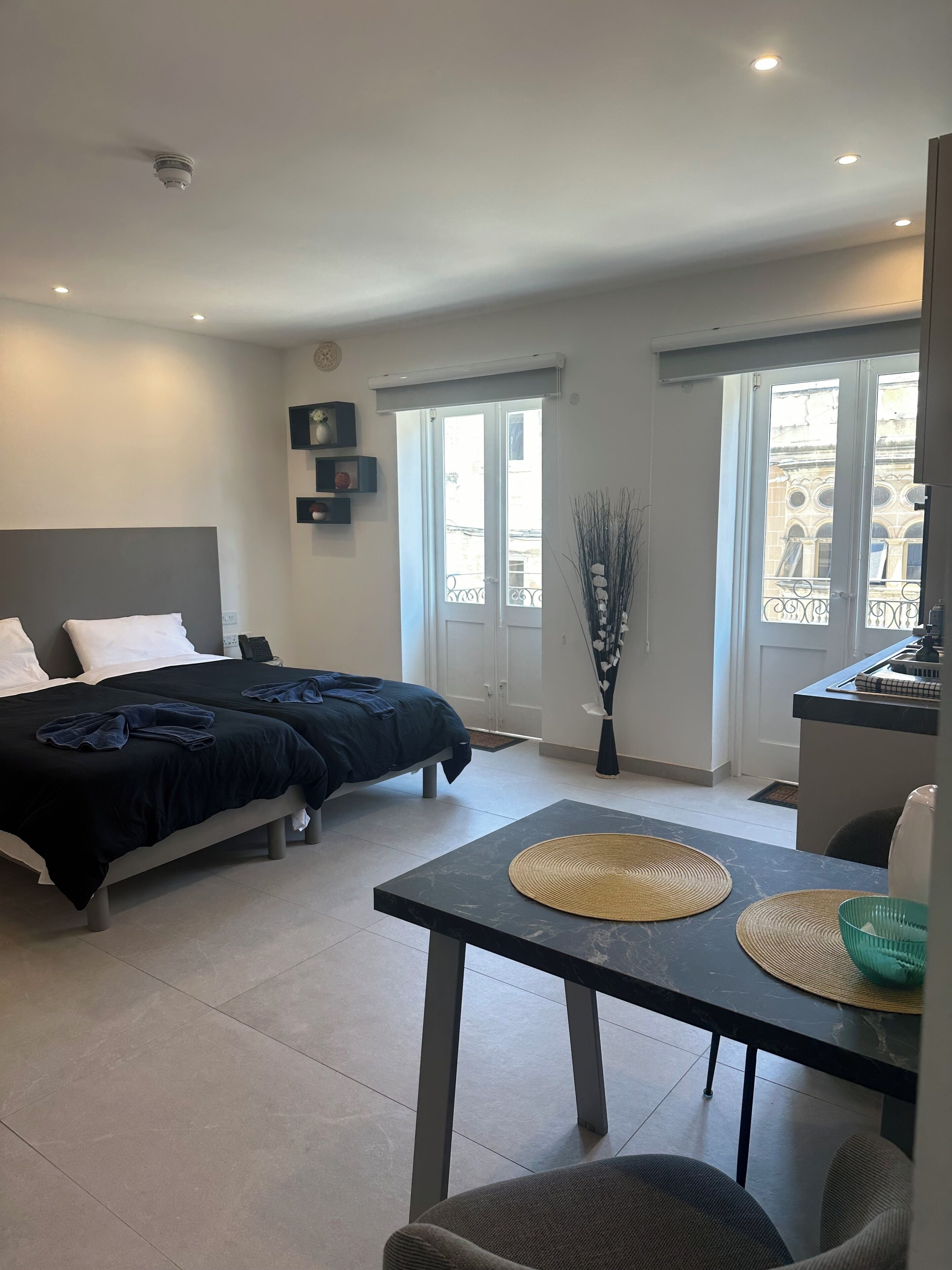 Une chambre d’hôtel moderne avec deux lits, une table à manger et une vue sur la ville.