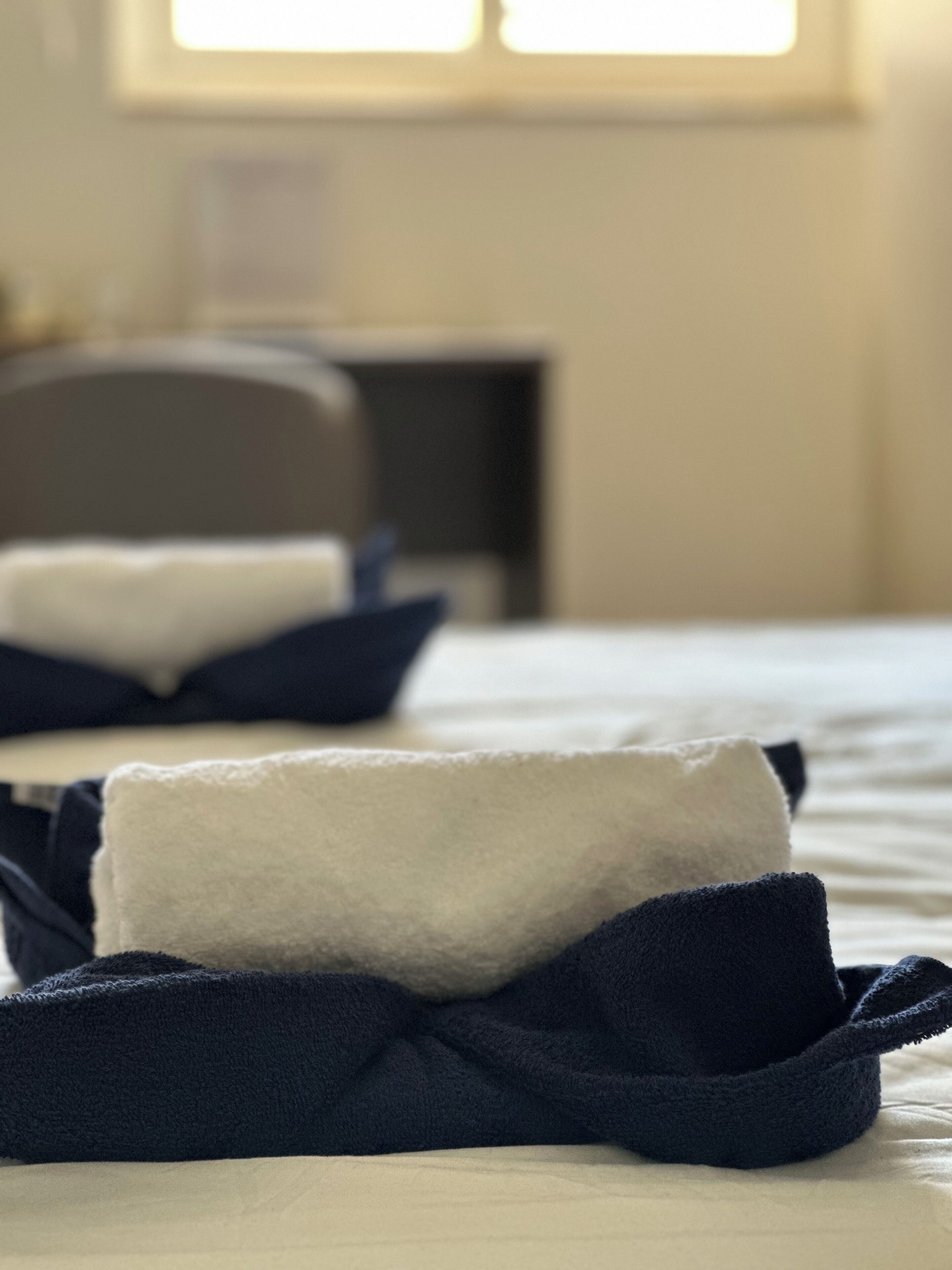 A bed with neatly folded towels and a chair in the background.
