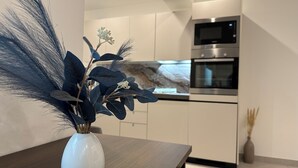 Una cocina moderna con armarios blancos, horno integrado y microondas.