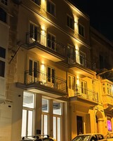 Un edificio de varios pisos con balcones, grandes ventanales y vista a la calle.