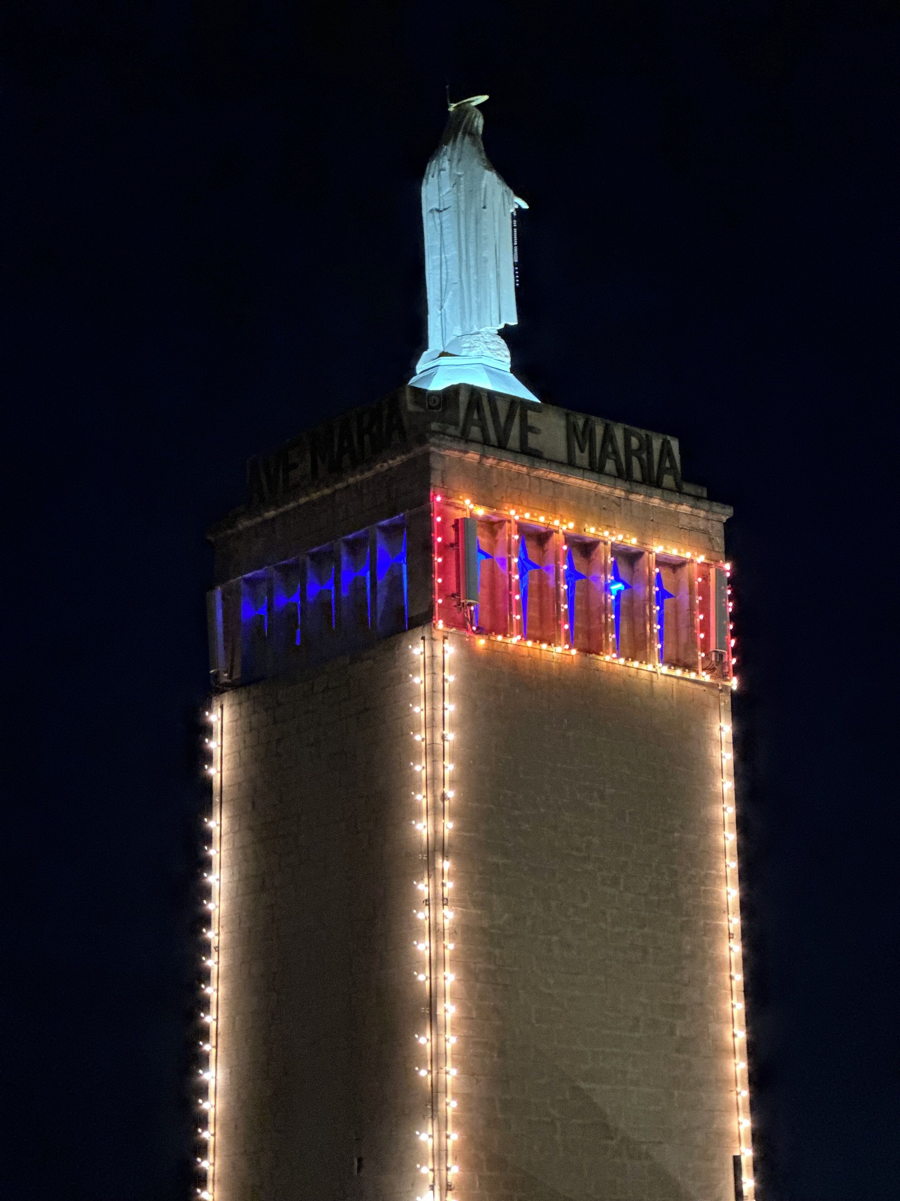 A tall building with "Maria Ave Maria" illuminated at the top.
