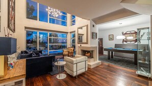 A modern living room with a fireplace, pool table, and large windows offering a view of the outdoors. - Luxury Villa Duchess with Pool (Crikvenica)