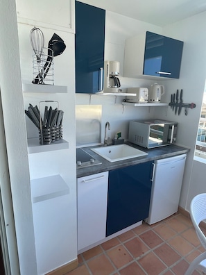 A compact kitchen with a sink, microwave, coffee maker, and utensils.