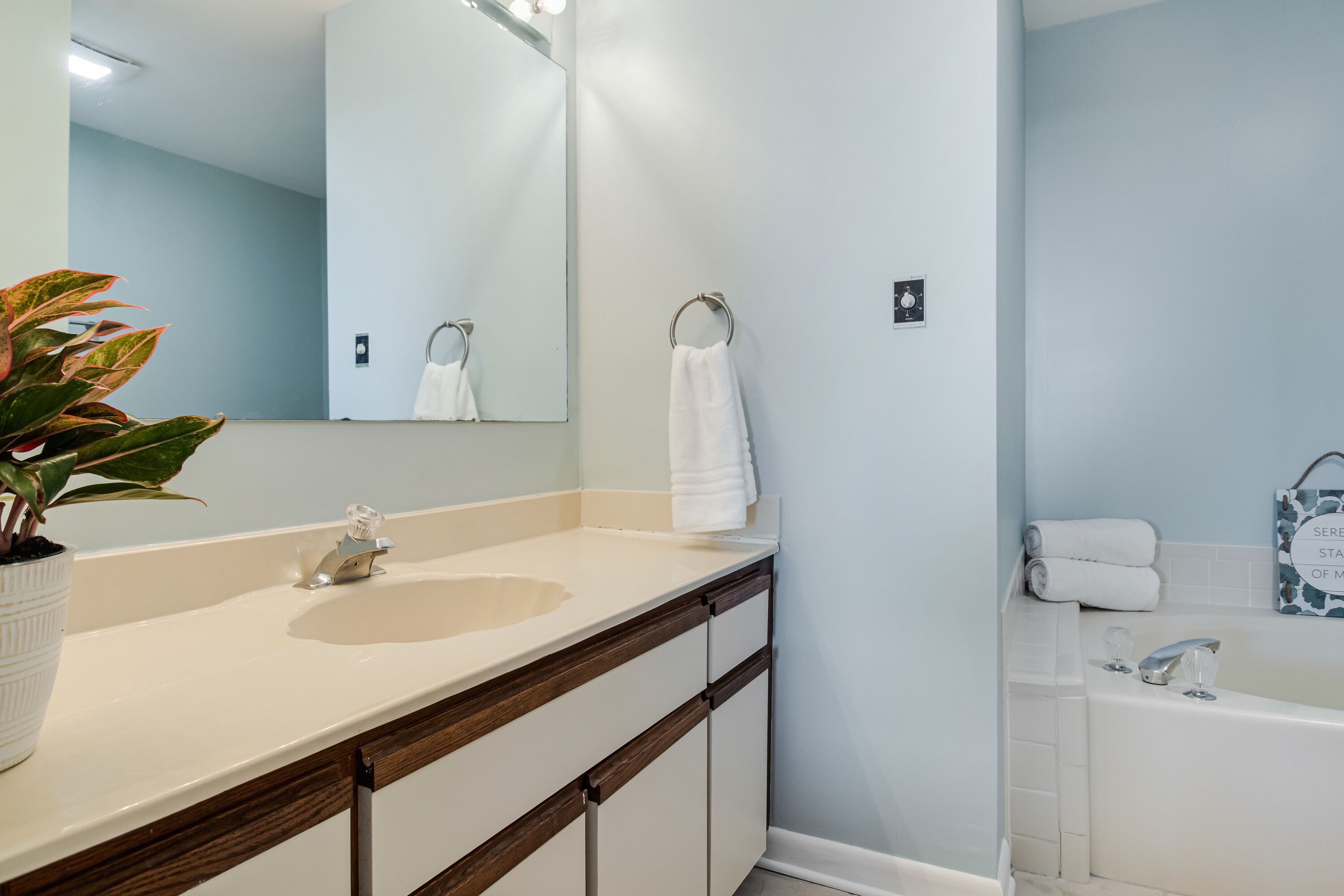 Une salle de bain équipée d’un lavabo, d’un miroir, d’un porte-serviettes et d’une baignoire.