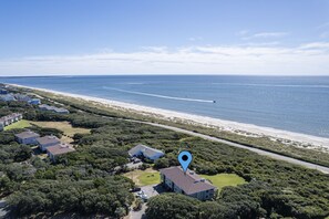 An aerial view of a coastal residential area with houses, a beach, and a road.