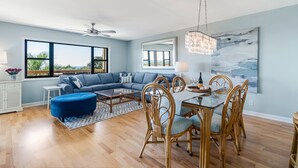 Un salon spacieux avec un canapé bleu, une table à manger et des chaises en osier.