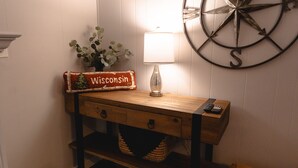 Ein hölzernes Konsolentische mit einer Lampe, einem dekorativen Schild und einem an der Wand befestigten Kompass.