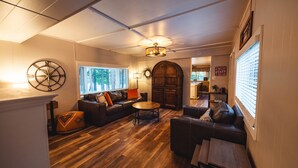 Ein gemütliches Wohnzimmer mit Holzboden, Ledersofas, einem Couchtisch und einer großen Holztür.