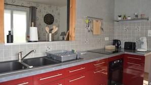 Cozinha com armários vermelhos, pia dupla e micro-ondas.