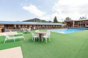 Zona de piscina con césped artificial, sillas de descanso y una mesa con sillas.