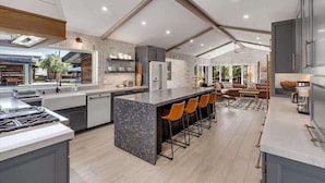 A modern kitchen with a large island, bar stools, and a view of the outdoors. - The Dragonfly - Healdsburg with Pool, Hot Tub and Tastings Included (Healdsburg)