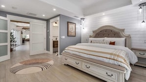 A bedroom with a large bed, a dresser, a nightstand, a framed picture on the wall, and a door leading to another room. - The Dragonfly - Healdsburg with Pool, Hot Tub and Tastings Included (Healdsburg)