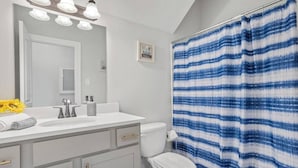 A bathroom with a white sink, a toilet, and a shower curtain with a blue and white pattern. - Stay with Style and Cheer for the Tigers -  CB1029 (Baton Rouge)