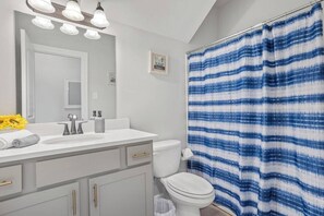 A bathroom with a white sink, a toilet, and a shower curtain with a blue and white pattern.